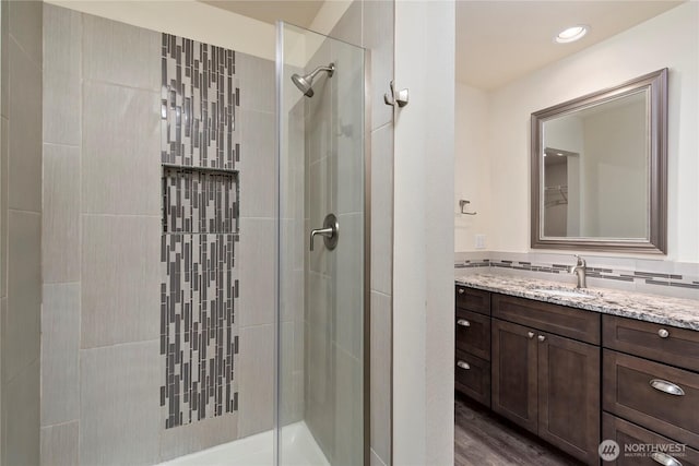 full bathroom featuring tasteful backsplash, a shower stall, vanity, and wood finished floors