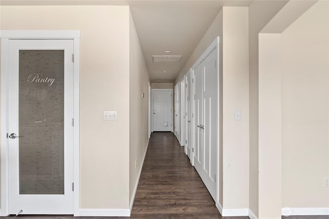 hallway with dark wood-type flooring, visible vents, and baseboards