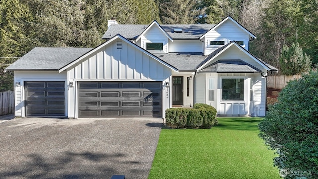 view of front facade with a garage, a front lawn, board and batten siding, and aphalt driveway