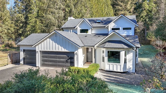 view of front of house featuring an attached garage, a shingled roof, fence, and board and batten siding