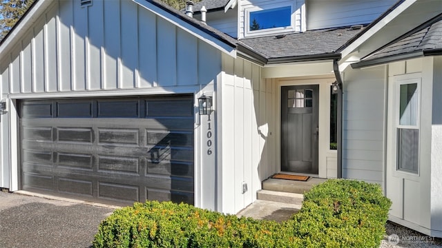 entrance to property with a garage, a shingled roof, aphalt driveway, and board and batten siding