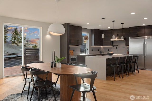 kitchen featuring a center island, stainless steel appliances, light wood-style flooring, a sink, and under cabinet range hood