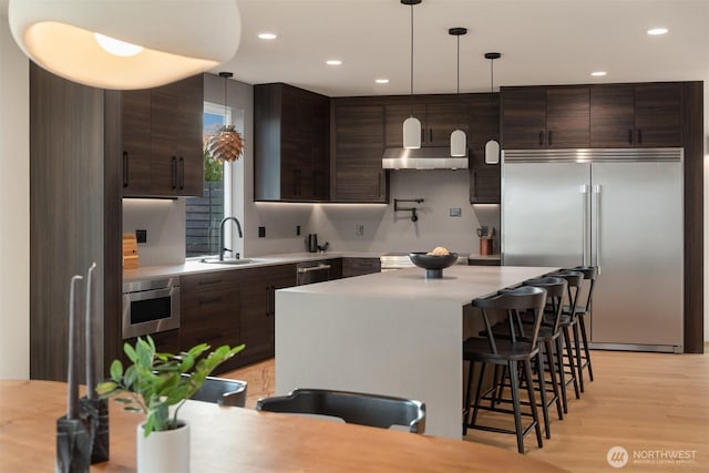 kitchen with a breakfast bar area, stainless steel appliances, a sink, and light countertops