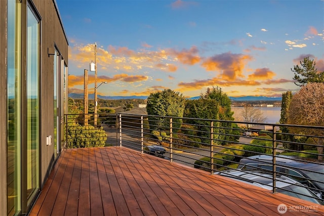 deck at dusk with a water and mountain view