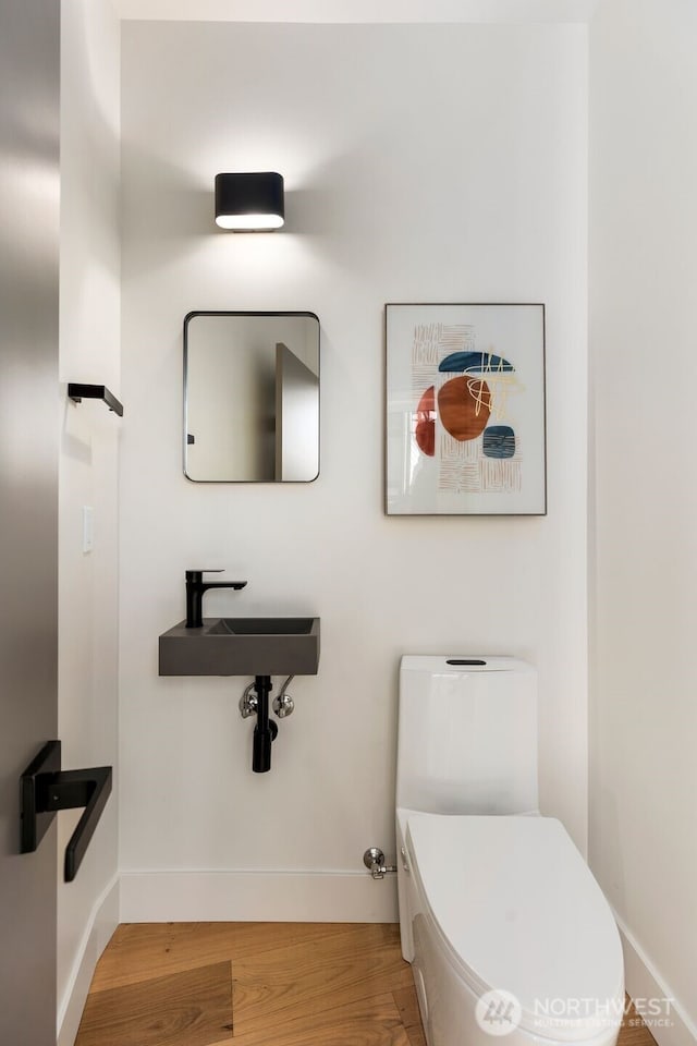 bathroom with wood finished floors, toilet, and baseboards