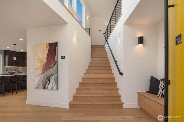 stairway with baseboards, wood finished floors, and recessed lighting