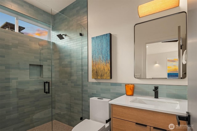 bathroom featuring toilet, a stall shower, tile walls, and vanity