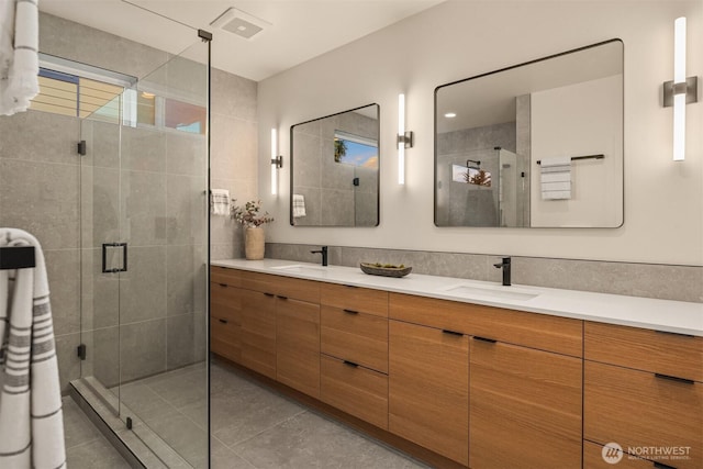 full bath featuring a stall shower, tile patterned floors, a sink, and double vanity