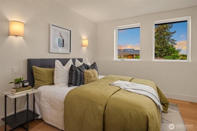 bedroom featuring multiple windows, baseboards, and wood finished floors