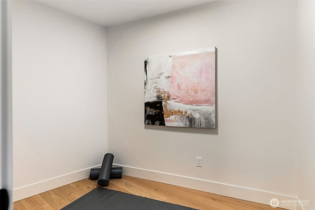 exercise room with baseboards and wood finished floors