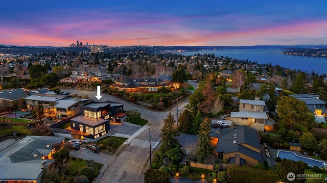 aerial view at dusk with a residential view and a water view