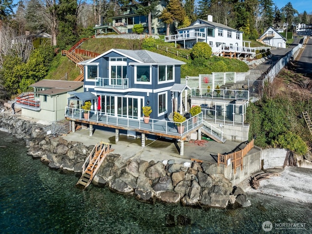 back of property with a deck with water view, a patio, and stairs