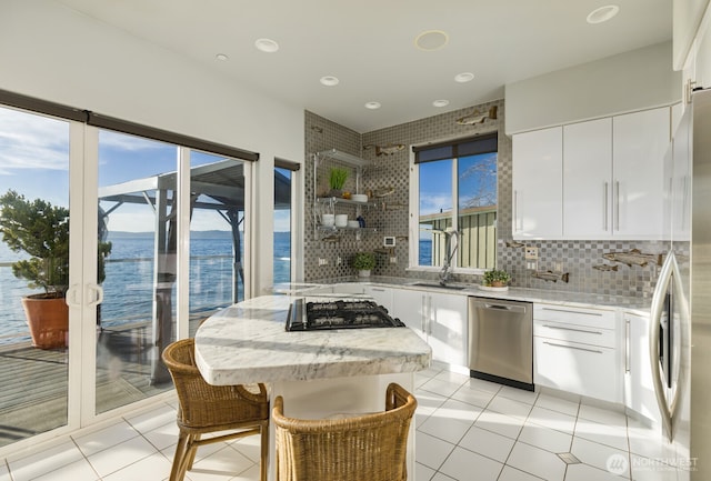 kitchen featuring tasteful backsplash, cooktop, white cabinetry, a sink, and dishwasher