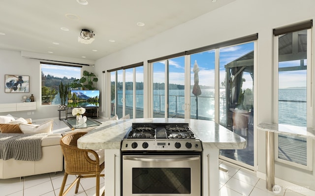 kitchen with open floor plan, light tile patterned flooring, and stainless steel range with gas cooktop