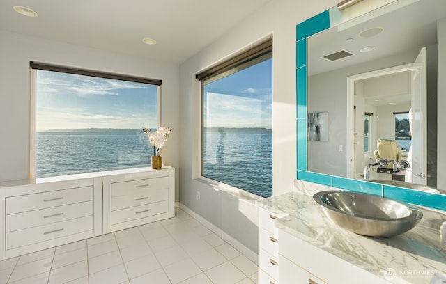 bathroom featuring tile patterned flooring, a water view, vanity, visible vents, and baseboards