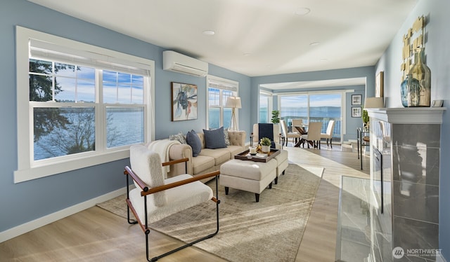 living area featuring a wall unit AC, wood finished floors, a high end fireplace, and baseboards