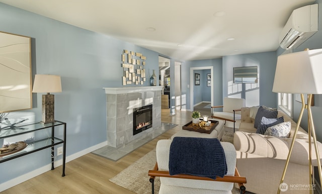 living room with a fireplace, baseboards, wood finished floors, and a wall mounted AC