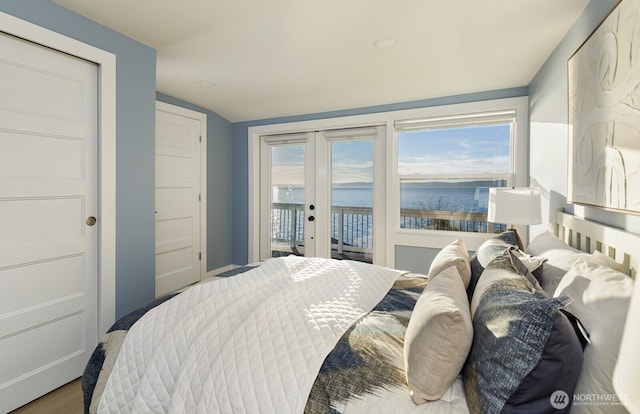 bedroom with access to outside, french doors, a water view, and wood finished floors