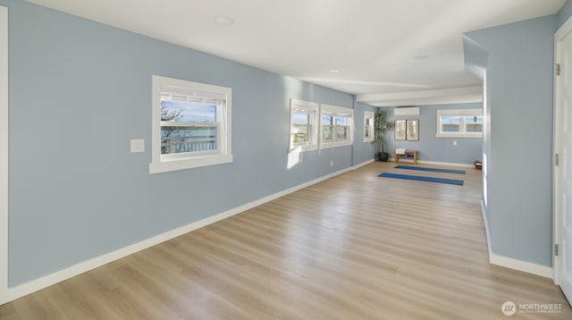 workout area with a wall mounted air conditioner, baseboards, and wood finished floors