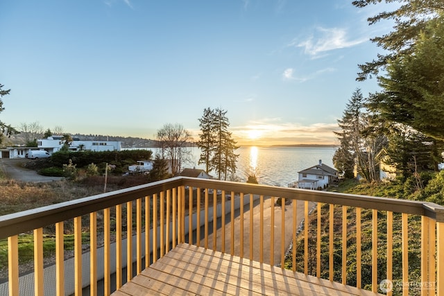 deck at dusk featuring a water view