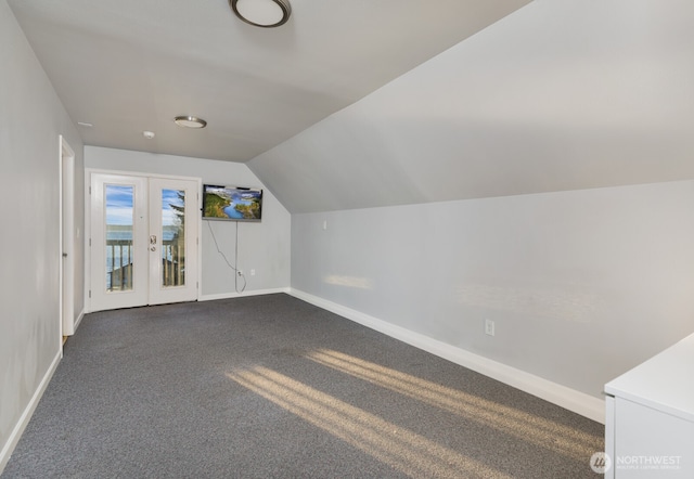 additional living space with lofted ceiling, baseboards, dark colored carpet, and french doors