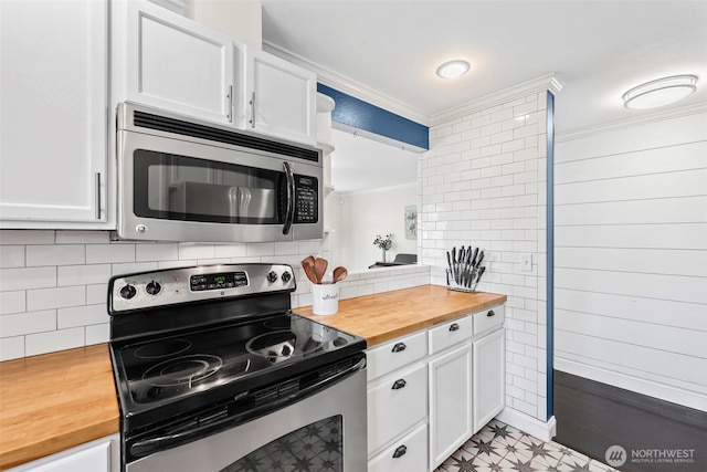 kitchen featuring white cabinets, butcher block counters, appliances with stainless steel finishes, and crown molding
