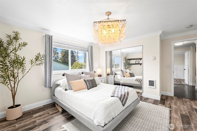 bedroom featuring crown molding, heating unit, wood finished floors, a chandelier, and baseboards
