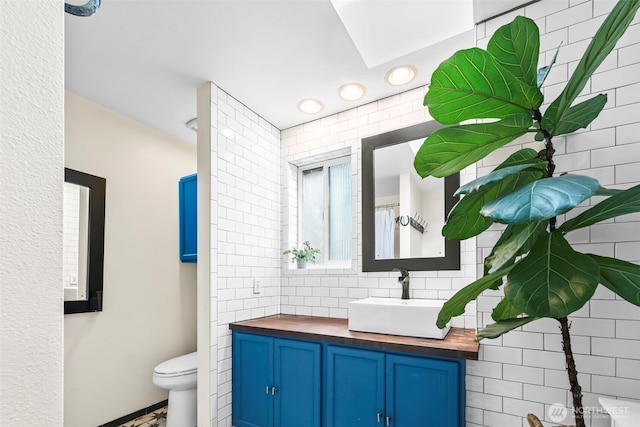 bathroom with toilet, vanity, and recessed lighting