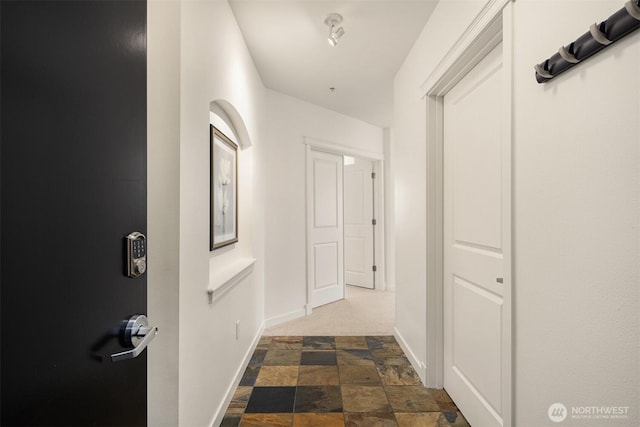 hallway featuring stone finish floor and baseboards