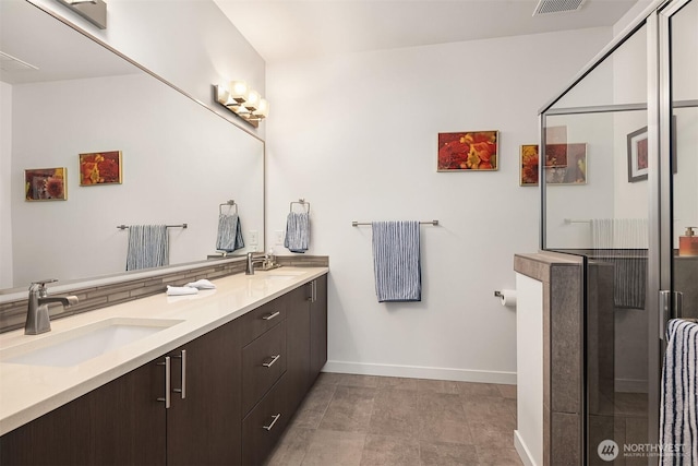 full bathroom with a stall shower, a sink, baseboards, and double vanity