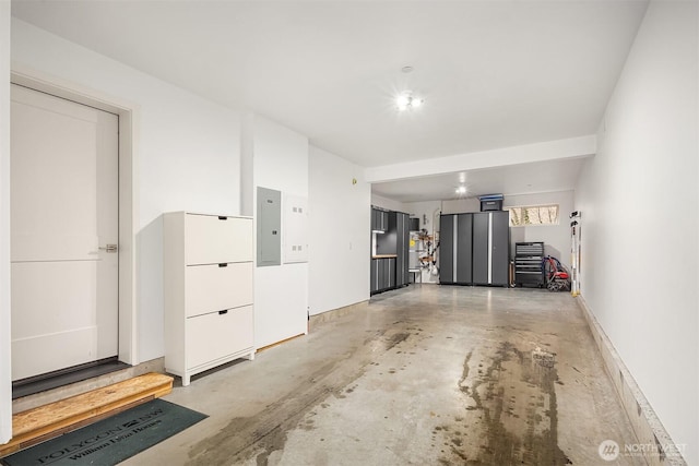 garage featuring electric panel and baseboards