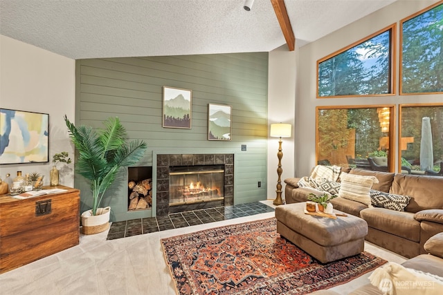 carpeted living area with wooden walls, a textured ceiling, and a tiled fireplace