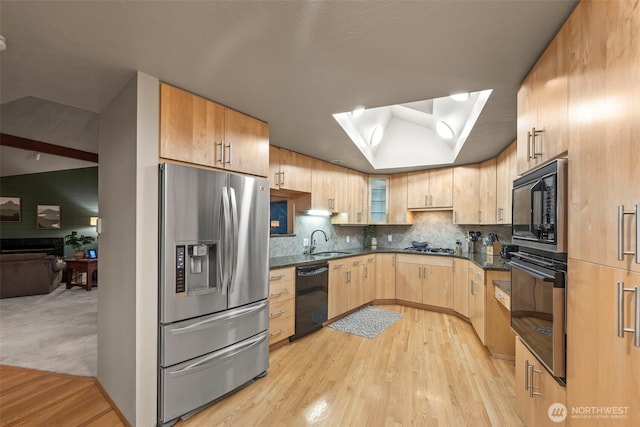 kitchen featuring tasteful backsplash, glass insert cabinets, light brown cabinetry, black appliances, and a sink