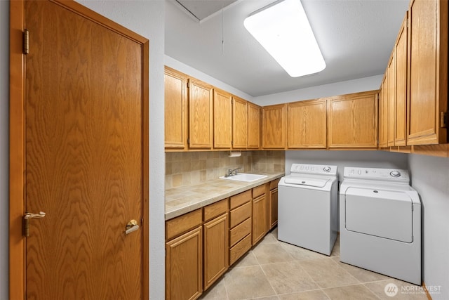 clothes washing area featuring light tile patterned floors, cabinet space, attic access, a sink, and independent washer and dryer