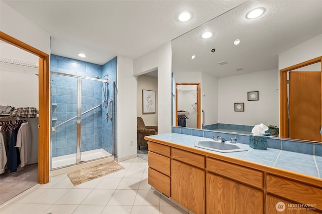 full bath with a walk in closet, recessed lighting, a shower stall, vanity, and tile patterned floors