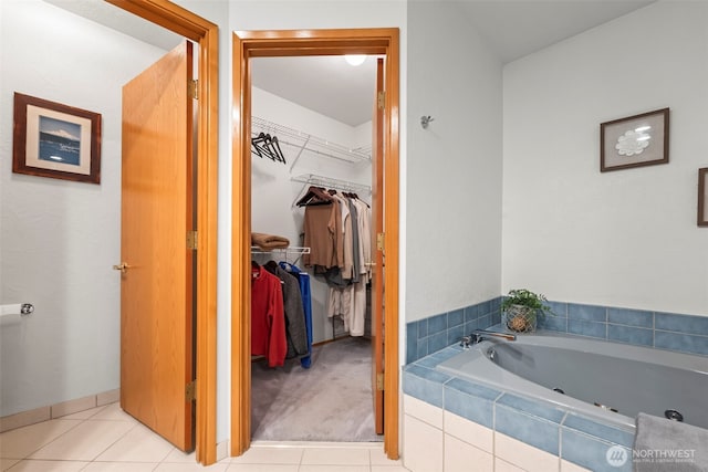 full bathroom featuring a walk in closet, a whirlpool tub, and tile patterned floors