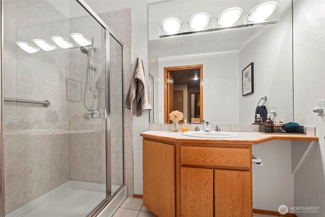 full bathroom with a stall shower, tile patterned flooring, and vanity