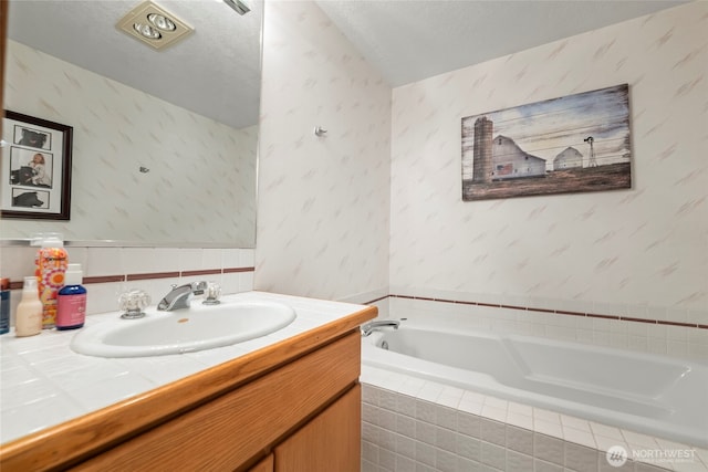 bathroom featuring a textured ceiling, a garden tub, vanity, and wallpapered walls