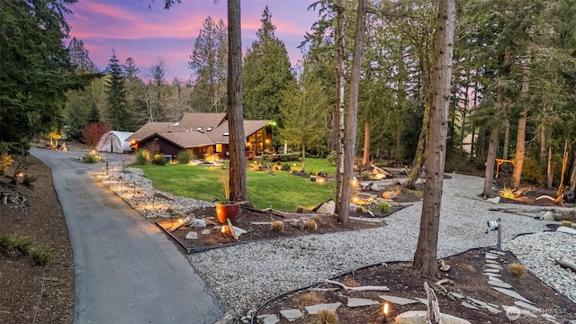 yard at dusk featuring a wooded view