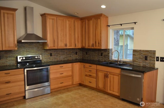 kitchen featuring lofted ceiling, decorative backsplash, appliances with stainless steel finishes, a sink, and wall chimney range hood