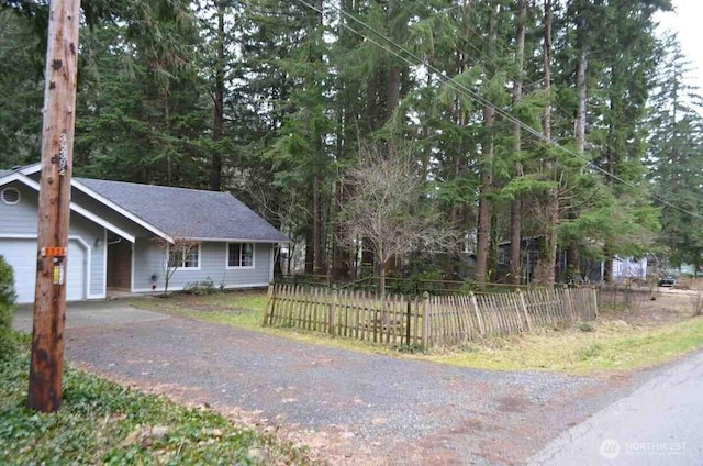 view of front of property featuring a fenced front yard, an attached garage, and aphalt driveway