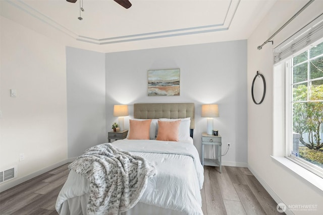 bedroom featuring ceiling fan, wood finished floors, visible vents, and baseboards