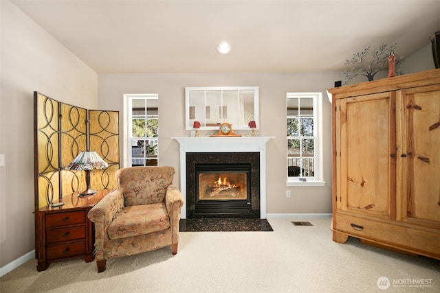 living area with carpet, a premium fireplace, baseboards, and visible vents