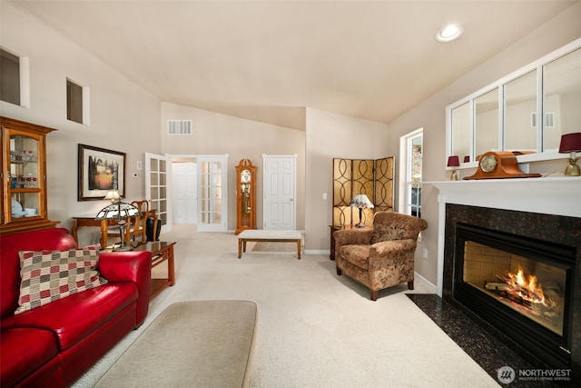 carpeted living area with lofted ceiling, a fireplace, visible vents, baseboards, and french doors