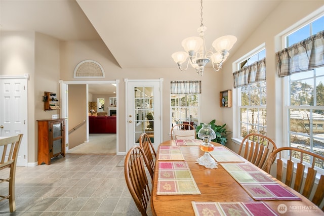 tiled dining area featuring high vaulted ceiling, plenty of natural light, baseboards, and an inviting chandelier