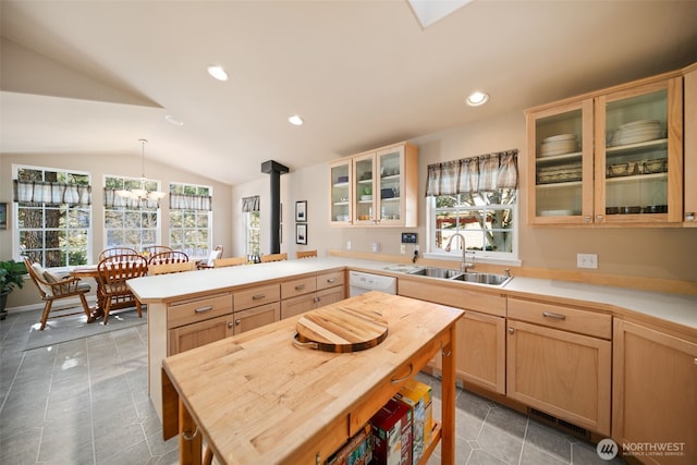 kitchen with lofted ceiling, a peninsula, light countertops, light brown cabinetry, and a sink