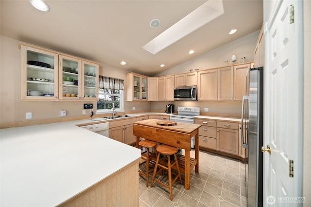 kitchen with light brown cabinets, recessed lighting, a sink, appliances with stainless steel finishes, and lofted ceiling with skylight