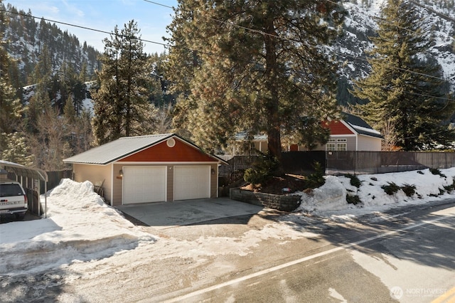 view of front of house with a garage, an outbuilding, and fence