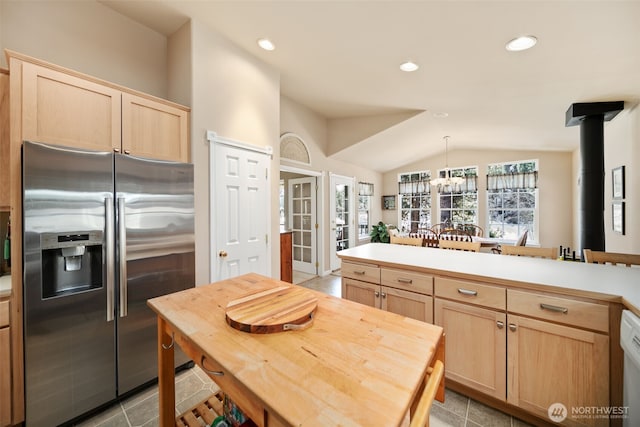 kitchen with stainless steel fridge, vaulted ceiling, light countertops, light brown cabinets, and recessed lighting