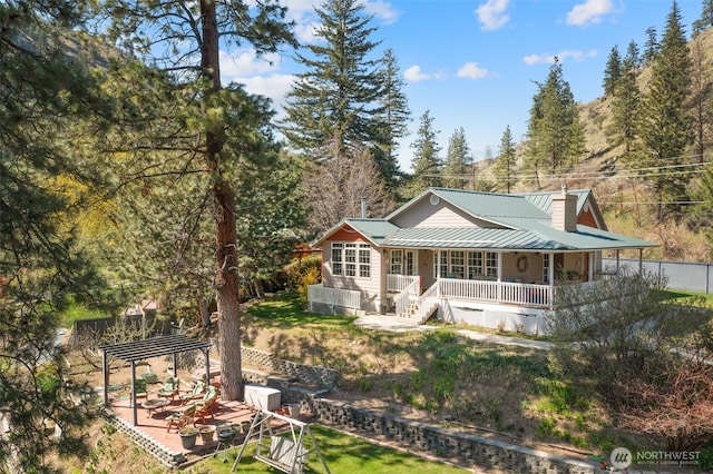 back of property with a pergola, a lawn, a porch, and metal roof